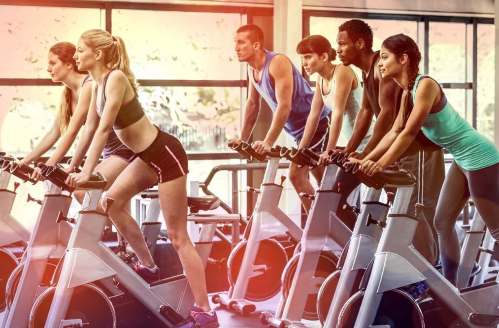 Kardiyo bisikletinde çalışan kadın ve erkekler