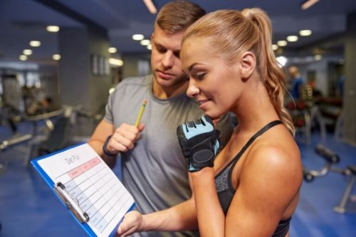 Eğitmeniyle spor salonunda konuşan bir kadın.