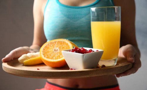 Tepside çeşitli meyveler ve bir bardak portakal suyu taşıyankadın