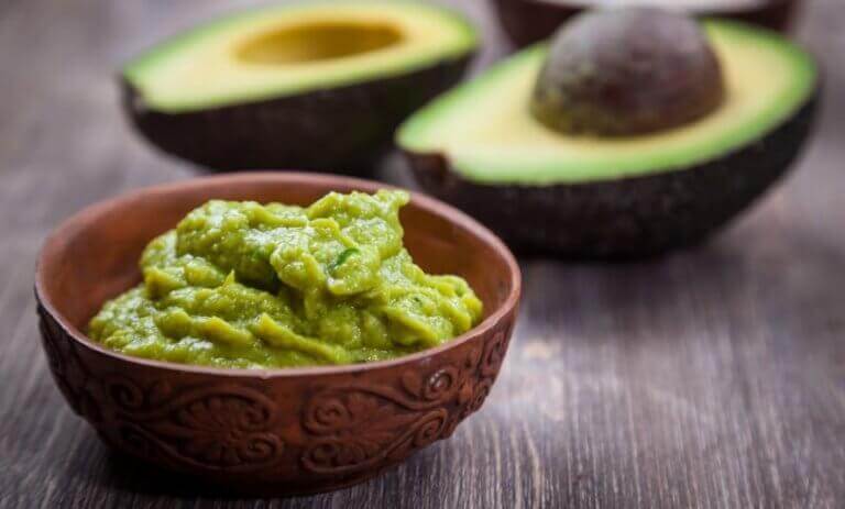 ikiye bölünmüş avokado ve bir kase guacamole