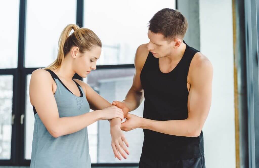 Kadın sporcunun dirseğine bakan antrenör