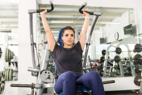 kadın alet üzerinde military press hareketi yapıyor
