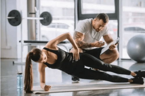 Bir antrenör eşliğinde spor yapan bir kadın.