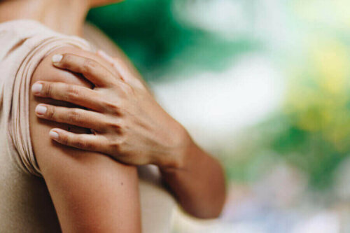 Omzunu tutan bir kadın.